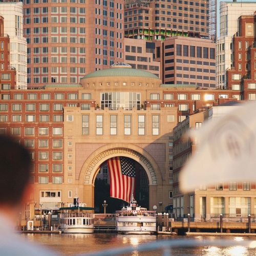 A person looks towards a building with an American flag over water.