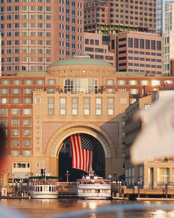 A person looks towards a building with an American flag over water.