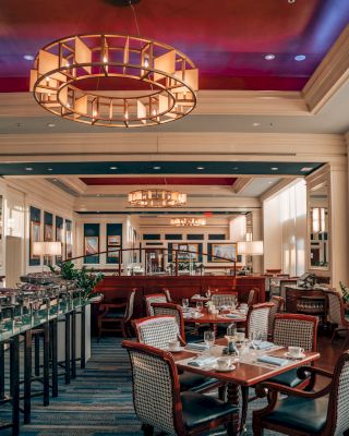 Elegant dining area with tables set for service and ornate chandelier above.