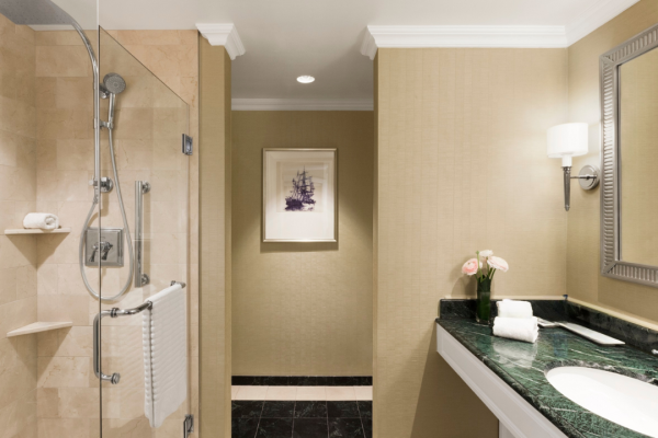 A modern bathroom with a shower, sink, mirror, and towel rail.