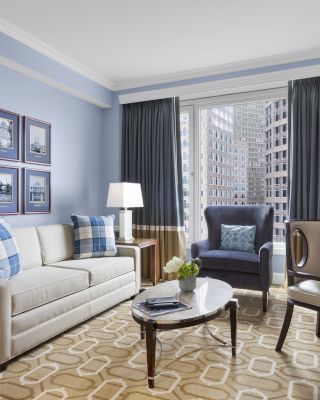 Elegant living room with sofas, lamps, coffee table, and city view.