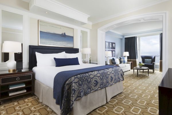 Elegant hotel room with a king-size bed, nautical-themed art, and ocean view.