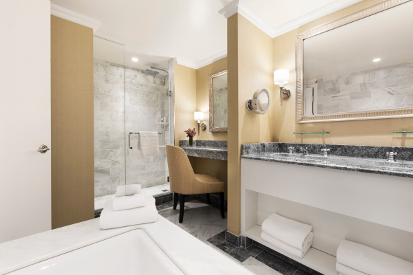 Modern bathroom with a tub, towels, a vanity area, and a chair.