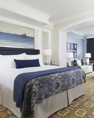 Elegant hotel room with a large bed, and ocean view windows.