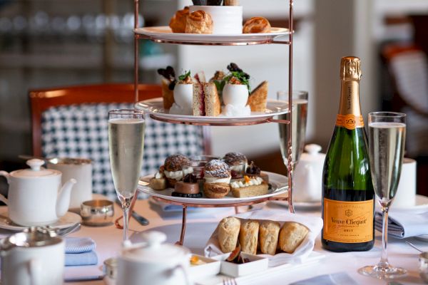 Elegant afternoon tea setup with treats, champagne, and tea.