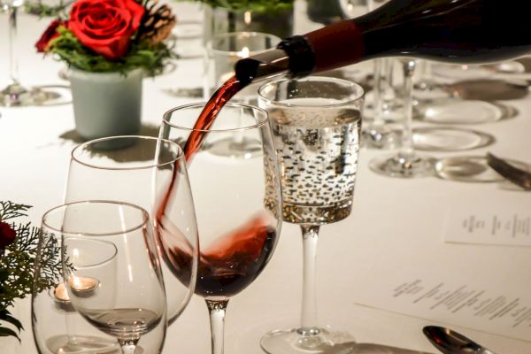 Elegant dining table with roses, wine pouring into a glass, and fine table.