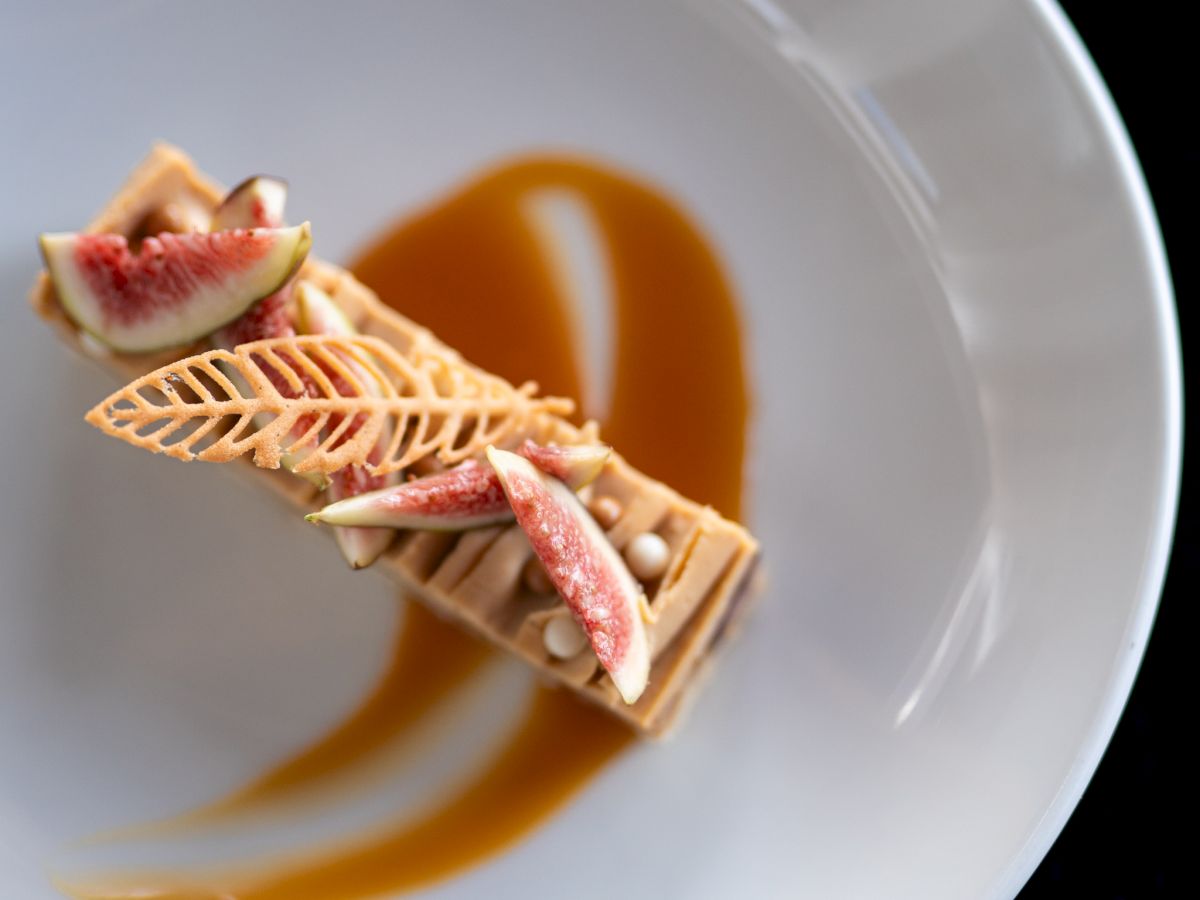 A plated dessert with figs and a decorative sauce on a white dish.