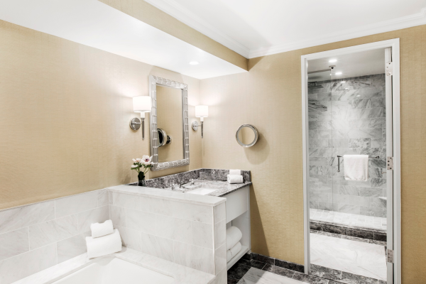 Modern bathroom with dual sinks, mirrors, and a glimpse of a shower area.