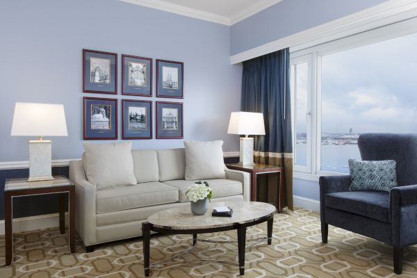 A living room with a beige sofa, blue armchair, table, and lamps.