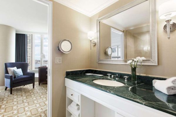 Elegant bathroom with a marble countertop, large mirror, and adjacent sitting area.