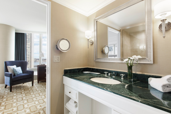 Elegant bathroom with a marble sink, large mirror, and a glimpse of a