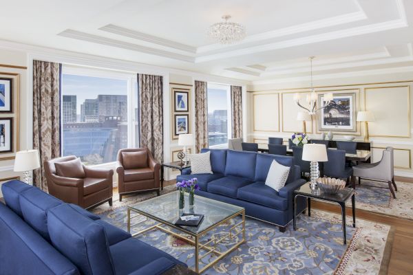 Luxurious room with blue sofas, chairs, chandelier, and city view.