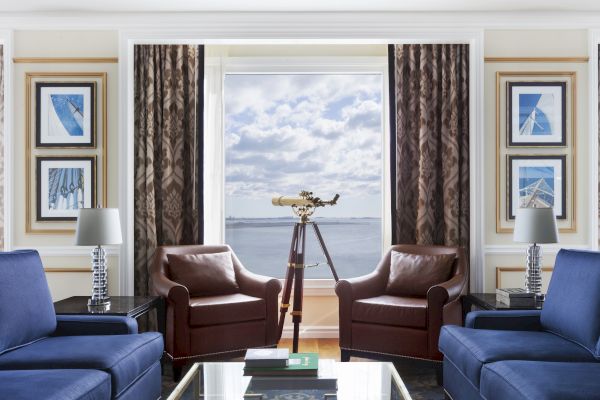 Elegant room with two blue sofas, a telescope, and harbor view.