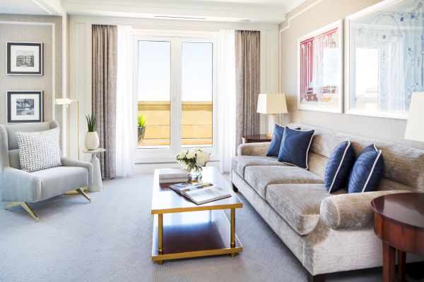 A well-lit living space with a sofa, chairs, table, and doors to a balcony.