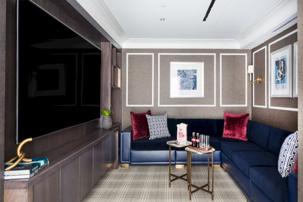 A modern room with a navy-blue sofa, television, framed art, and a coffee table.