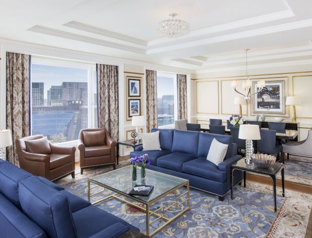 Elegant living room with blue sofas, brown chairs, and large windows.