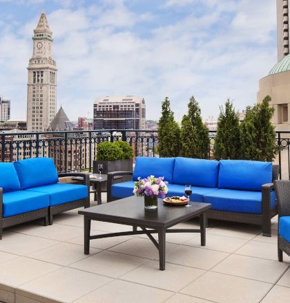 Outdoor patio with blue sofas, city skyline, and a clock tower in the background