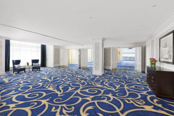 Elegant room with blue patterned carpet, columns, chairs, and natural light