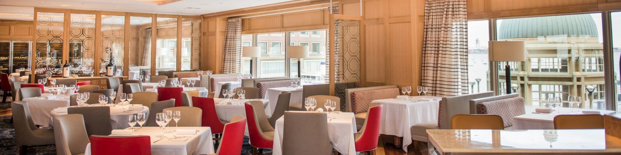 Elegant dining room with arranged tables, red and cream chairs, and modern lighting