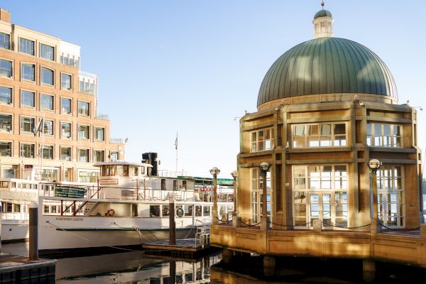 Urban waterfront scene with buildings, a dome structure, and moored boats.