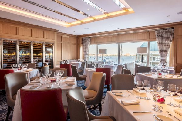 Elegant dining room with set tables, chairs, and a view of the water