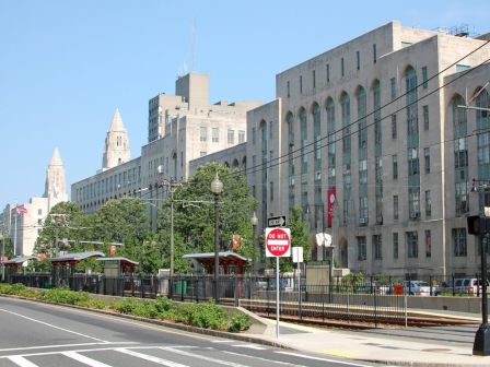 A city street view with tram lines, buildings in the background, and a clear