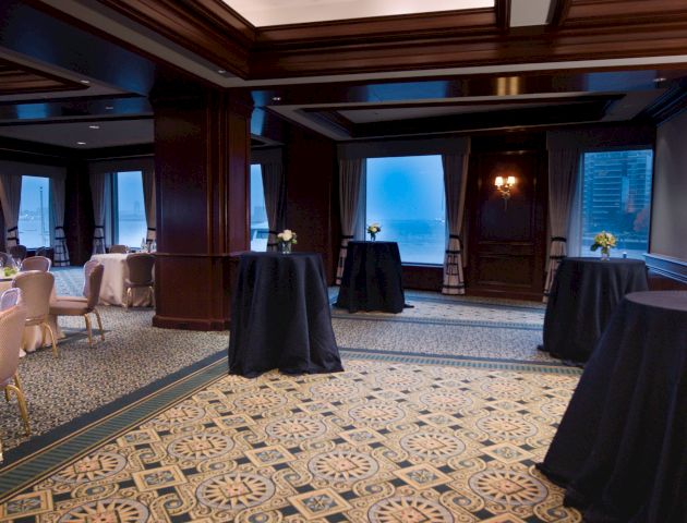 Elegant room with tables, chairs, decorative carpet, and ocean view windows.