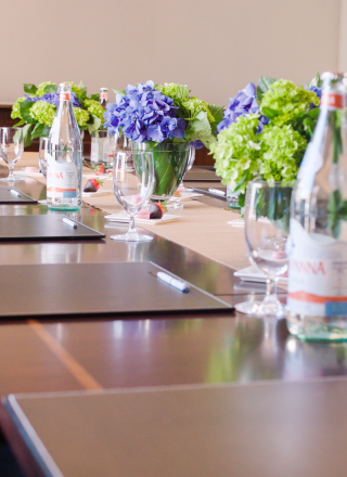 A modern boardroom with a long table, chairs, water bottles, glasses,