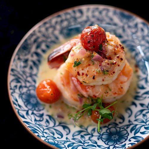 Gourmet dish with shrimp, garnishes, on patterned plate.