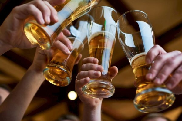 Several people are raising glasses of beer in a toast, likely celebrating or enjoying a social gathering.