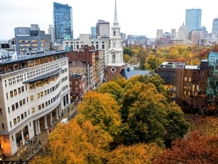 Urban landscape with autumn trees and historic church spire.