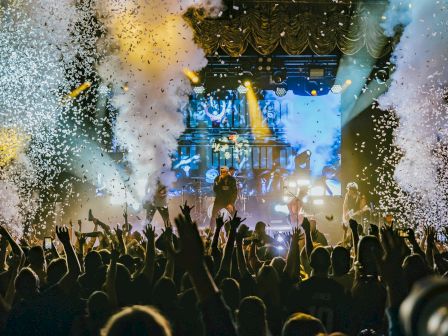 A concert with a jubilant crowd, stage lights, and confetti.