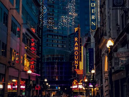 A city street at dusk with neon signs, a car, and lit buildings.