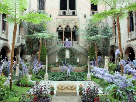 Lush courtyard with greenery, arched walkways, and a central statue