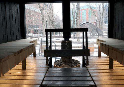 The image shows the interior of a wooden sauna with benches on both sides, and a heater with stones in the center.