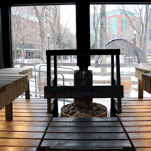 The image shows the interior of a wooden sauna with benches on both sides, and a heater with stones in the center.