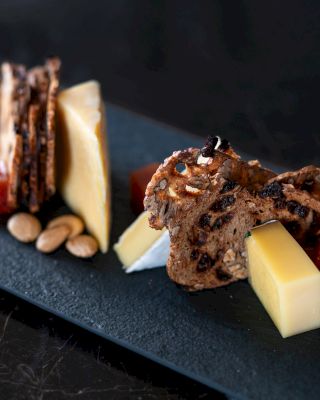 Gourmet cheese and crackers, some nuts, and fruit jelly on a slate board