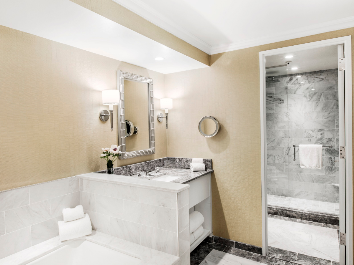 A modern bathroom with a vanity, mirror, and shower visible.