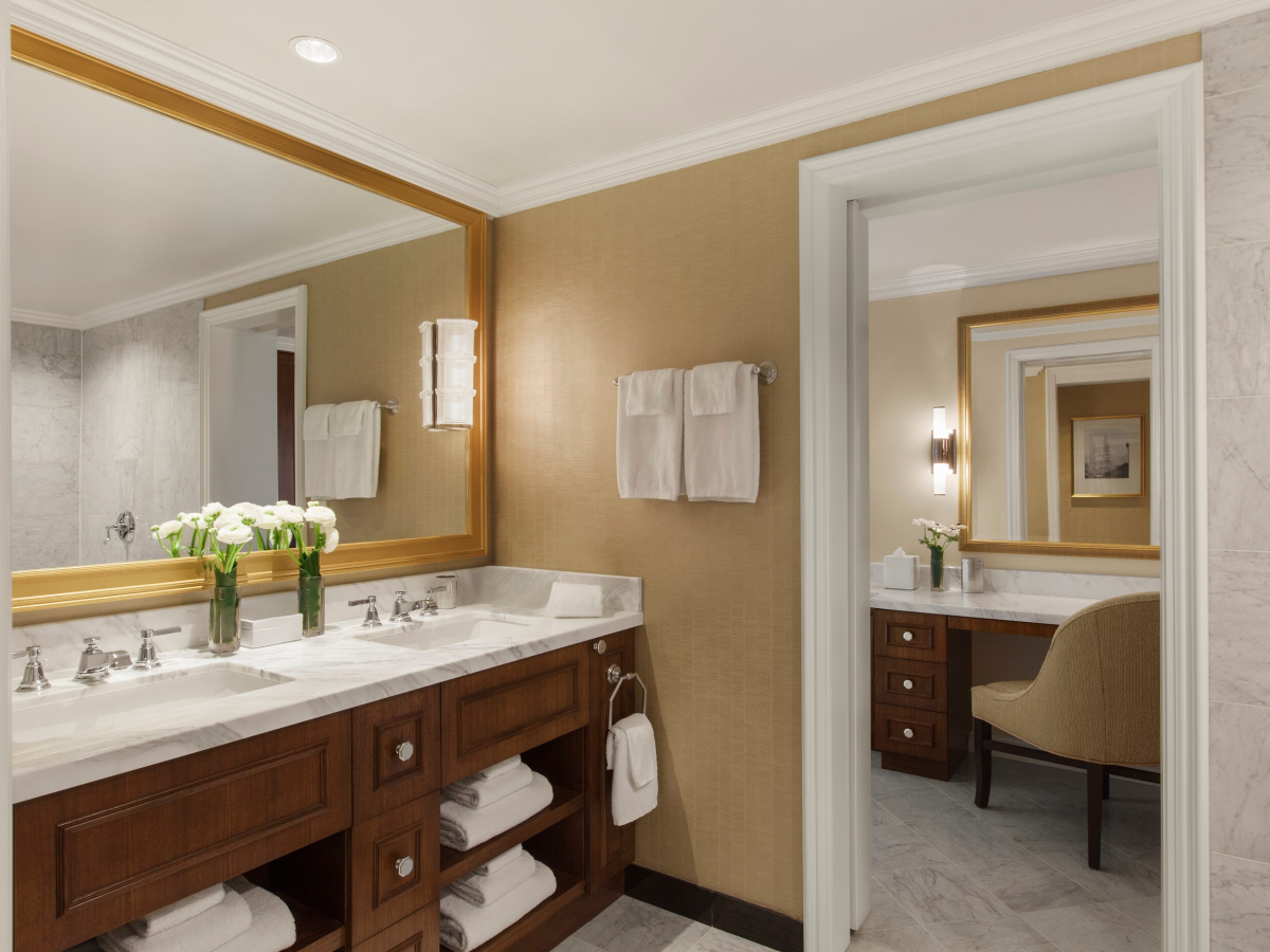 Elegant bathroom with double sinks, mirror, fresh flowers, and towels.