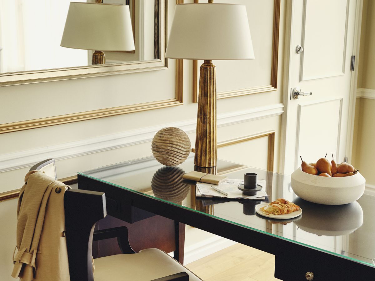 An elegant desk with a chair, lamps, decorative objects, and a fruit bowl.