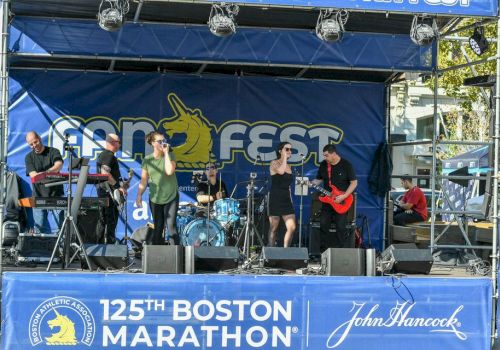 A band performs on stage at the 125th Boston Marathon with the backdrop reading 