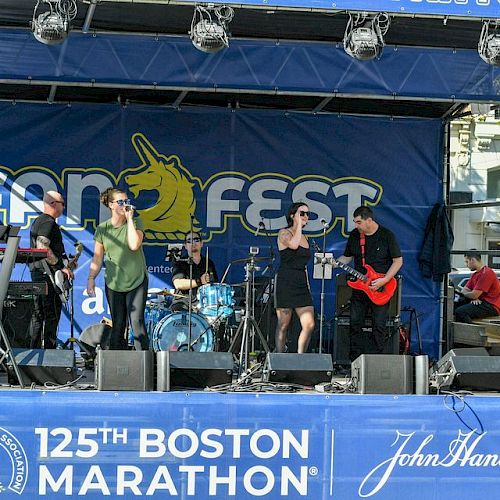 A band performs on stage at the 125th Boston Marathon with the backdrop reading 