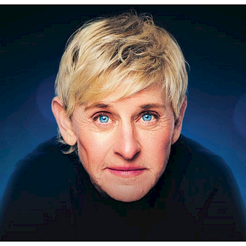 A person with short blonde hair and blue eyes is looking directly at the camera against a blurred dark blue background.