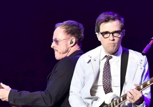 Two men performing in concert holding guitars