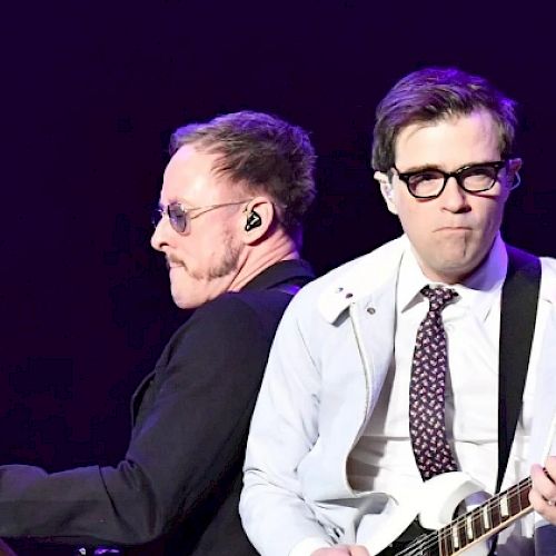 Two men performing in concert holding guitars