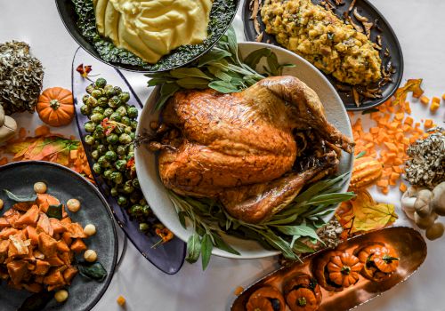 A bountiful Thanksgiving meal with a roasted turkey, mashed potatoes, stuffing, Brussels sprouts, sweet potatoes, and decorative pumpkins.